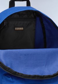 Intérieur d'un sac à dos en toile bleu avec une poche zippée noire, ornée d'une étiquette de logo et d'une texture lisse ; comprend une doublure en tissu contrastant.