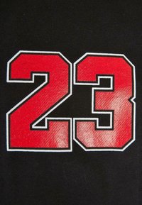 Black fabric displays bold red numbers "23" with a gloss finish, outlined in white, creating a high-contrast design.