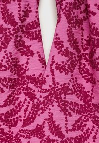 Tessuto rosa con un motivo floreale testurizzato nelle tonalità di lampone scuro e bordeaux, dall'aspetto morbido e leggermente stropicciato.