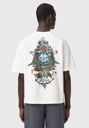 Homme portant un T-shirt blanc avec un graphique complexe multicolore de fleurs, de crâne et de bannière au dos portant l'inscription "Envoyez-moi une carte postale AllSaints."