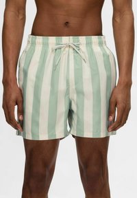 Gestreifte Badeshorts in Hellgrün und Creme, aus leichtem Stoff gefertigt, mit elastischem Bund und verstellbarem Kordelzug.