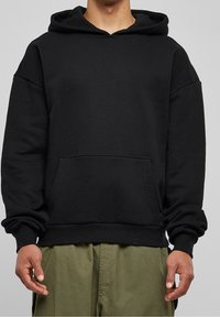 Czarna bluza z kapturem z przodu, z kieszenią, o luźnym kroju i ściągaczami przy mankietach. Wykonana z miękkiego materiału, charakteryzuje się gładką fakturą i minimalistycznym wzornictwem.