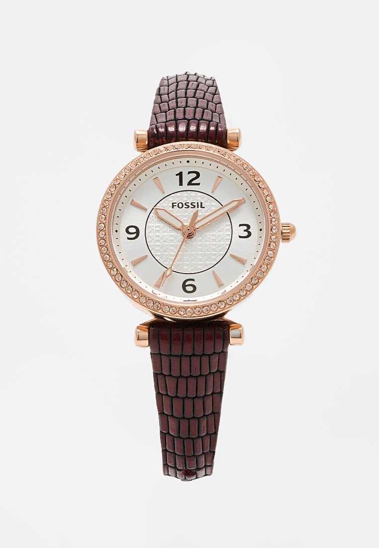 Reloj Fossil redondo con un dial plateado, acentos en oro rosa y una correa de cuero texturizado de color burdeos oscuro. Presenta detalles similares a gemas alrededor del bisel.