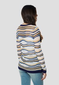 Hosszú ujjú kötött pulóver, fehér, kék, sárga és tengerészkék színekben húzódó többszínű vízszintes csíkokkal. Nyitott szövésű textúrával és bordázott mandzsettákkal.