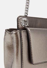 Borsa a tracolla argentata in metallo con finitura testurizzata, dotata di chiusura a pattina, accessori in argento e tracolla a catena. Design piccolo e compatto.