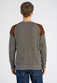 Suéter de punto gris claro con un patrón texturizado, que presenta acentos en cuero marrón en los hombros y un cuello acanalado. Corte relajado.