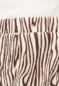 Κοντινό πλάνο πτυχωτού υφάσματος με κάθετες καφέ και μπεζ ρίγες που μοιάζουν με ζέβρα.