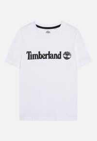 Camiseta de algodón blanca con un logotipo y gráfico de árbol negros de "Timberland". Manga corta, cuello redondo y una textura suave.