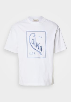 T-shirt in cotone bianco con un design grafico blu chiaro che presenta la scritta "Calvin NY Klein" in un font curvo. Maniche corte e scollatura a girocollo.