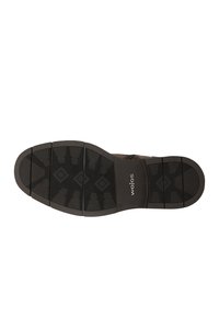 Sohle eines dunkelbraunen Schuhs mit segmentierten Profilmustern und dem "wojas"-Logo in Weiß nahe der Ferse gedruckt.