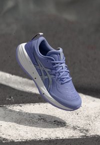 Μωβ αθλητικό παπούτσι με υφασμάτινη επένδυση, κορδόνια και λευκή ενδιάμεση σόλα. Διαθέτει διακριτική σήμανση και ελαφριά σχεδίαση.