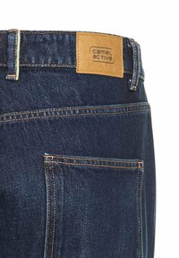 Dunkelblaue Jeans aus Denim mit einem beigefarbenen Lederlabel "camel active". Sie verfügen über kontrastierende Nähte und ein Detail an der hinteren Tasche.