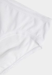 Witte katoenen slip met een golvende elastische tailleband en een gladde textuur, met een gedeeltelijk uitzicht op de stof en de afwerking van de rand.