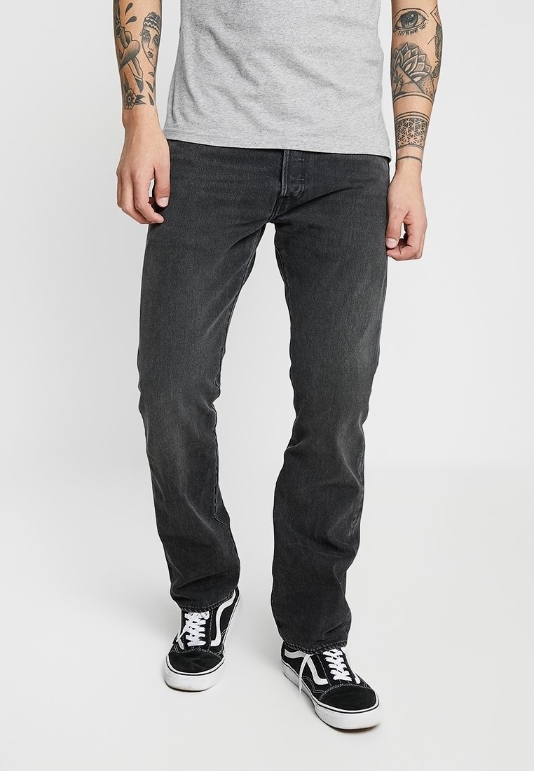 Svarta denimjeans med rak passform, med en klassisk femficksdesign, bärs med en grå t-shirt och svarta sneakers.