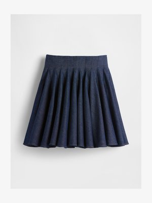 Tumši zils plisēts svārks, izgatavots no džinsa auduma. Tam ir augsta vidukļa josla un izplestos formas, ar redzamām šuvēm gar plisēm.