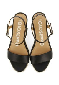Sandalias de cuero negro con una amplia correa en el tobillo, diseño de punta abierta y una suela texturizada. Presentan una hebilla y un forro beige con el logo de la marca.