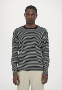 Langermet skjorte i svart og hvitt horisontalt stripete design, laget av mykt stoff, har rund hals og en liten brystlomme.