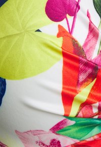 Tecido com um vibrante padrão floral multicolorido sobre um fundo branco, com uma textura suave e ligeiramente brilhante e formas curvas.