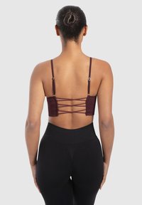 Sujeción trasera burdeos con tirantes ajustables delgados y tejido acanalado. Presenta un diseño entrecruzado en la parte posterior y una cinturilla cómoda.