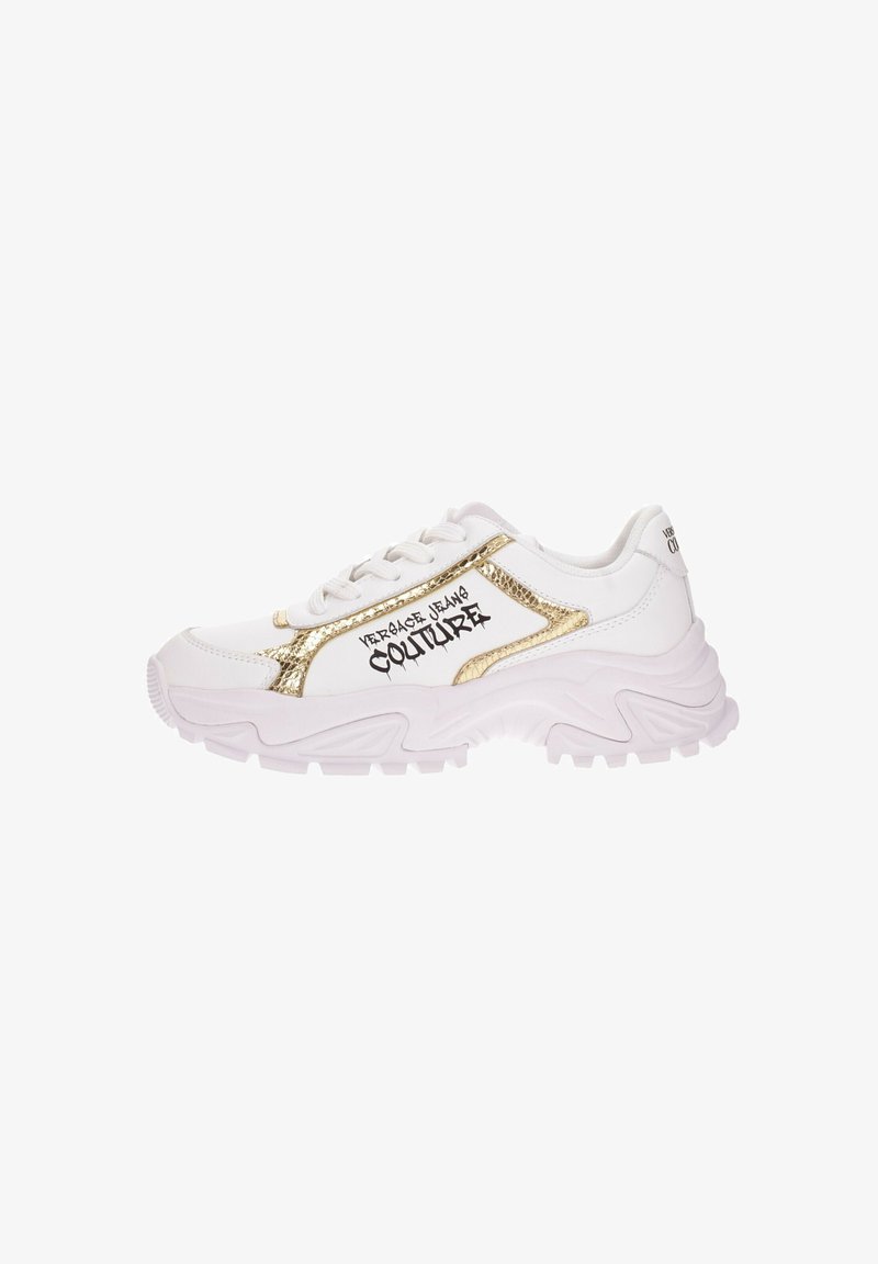 Zapatilla blanca con acentos dorados y texto negro. Presenta una parte superior texturizada, suela gruesa con un patrón de olas y cordones. Tiene un diseño contemporáneo.