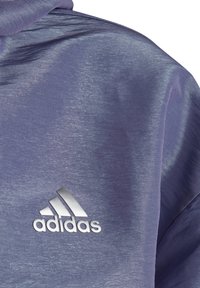 Fialová mikina Adidas s hladkou texturou, se stříbrným logem na oblasti hrudníku a minimalistickým designem. Měkká a hladká tkanina.
