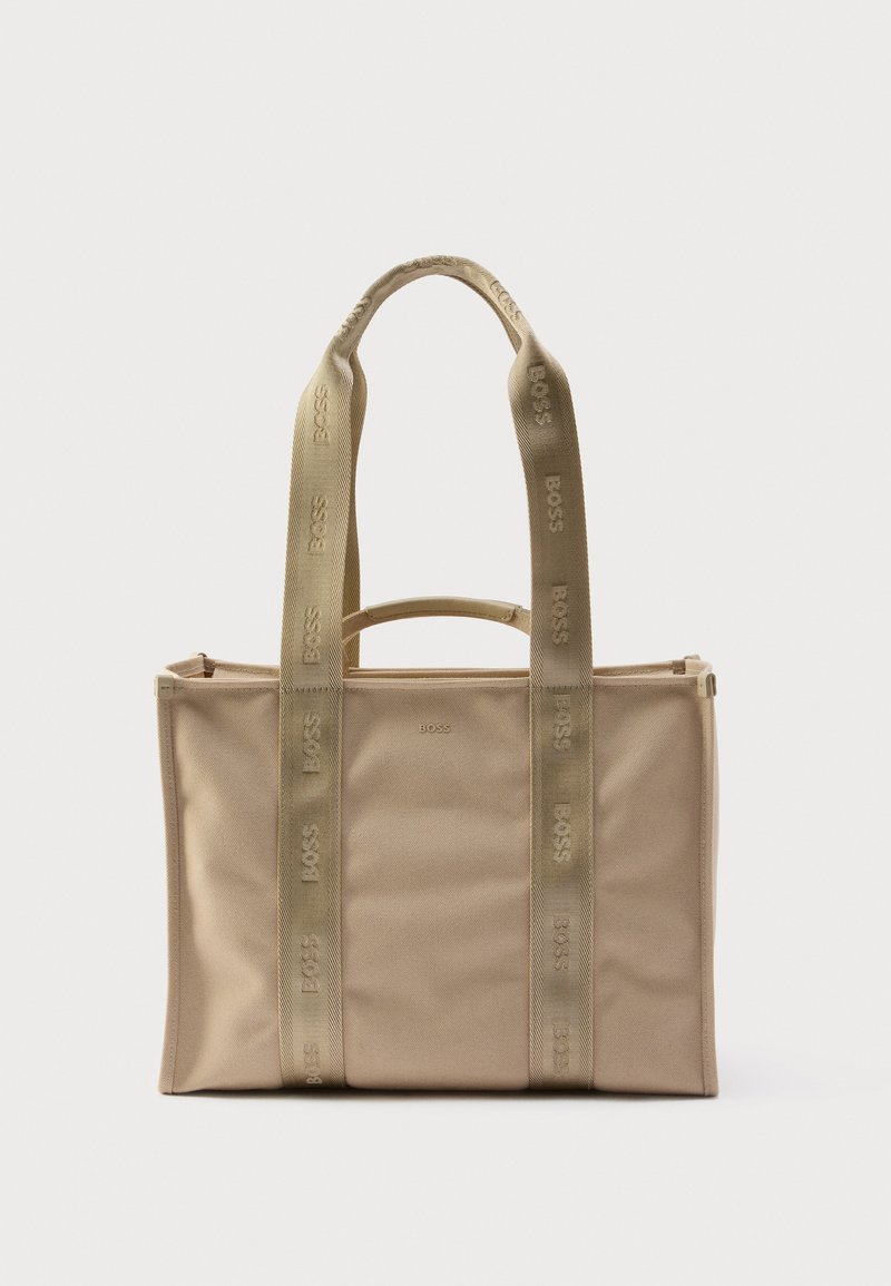 Beżowa torba typu tote o usztywnionej konstrukcji, wyposażona w podwójne górne uchwyty i markowe paski z płótna. Gładka tkanina o subtelnej fakturze.