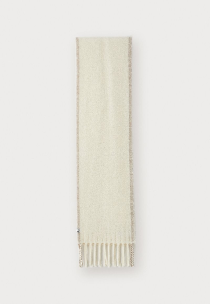 Écharpe crème en matériau doux, avec une bordure beige et des extrémités à franges. La texture paraît lisse et chaude.
