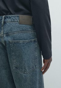 Dżinsy z denimu w blado-niebieskim kolorze z nadrukiem na skórzanej metce "Massimo Dutti". Charakteryzują się detalami na tylnej kieszeni i luźnym krojem.