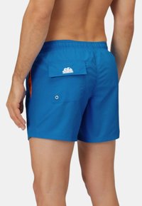Pantaloni da bagno blu realizzati in tessuto leggero, dotati di una cintura elastica, tasche laterali e una tasca posteriore con un dettaglio del logo bianco.