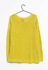 Långärmad stickad tröja i klargul färg. Har en vid halsringning, ribbad fåll och ett löst, texturerat vävt mönster. Hänger på en svart krok.