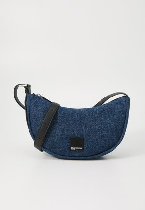 Temna modra denim torba za ramo polkrožne oblike, s črnim usnjenim ročajem in kvadratnim logotipom na sprednji strani. Zapiranje na zadrgo.