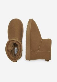 Botas de tobillo de ante marrón con una suela texturizada, forro interior acolchado y detalle de costura visible, que presentan un diseño de corte bajo y una lengüeta trasera.