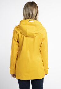Sárga vízálló dzseki kapucnival, sima felülettel, állítható nyakzsinórral és fekete fém kiegészítőkkel. Elegáns, modern dizájn jellemzi.