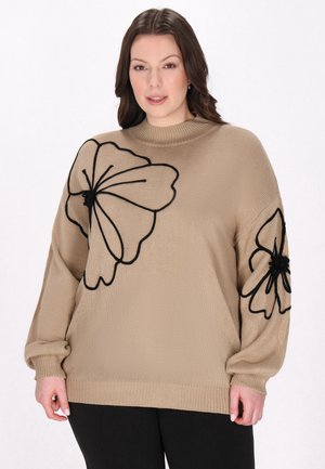 Beige gestrickter Pullover mit schwarzer Blumenstickerei, der übergroße Blumen und einen enganliegenden Rollkragenstil aufweist. Lange, lässige Ärmel.