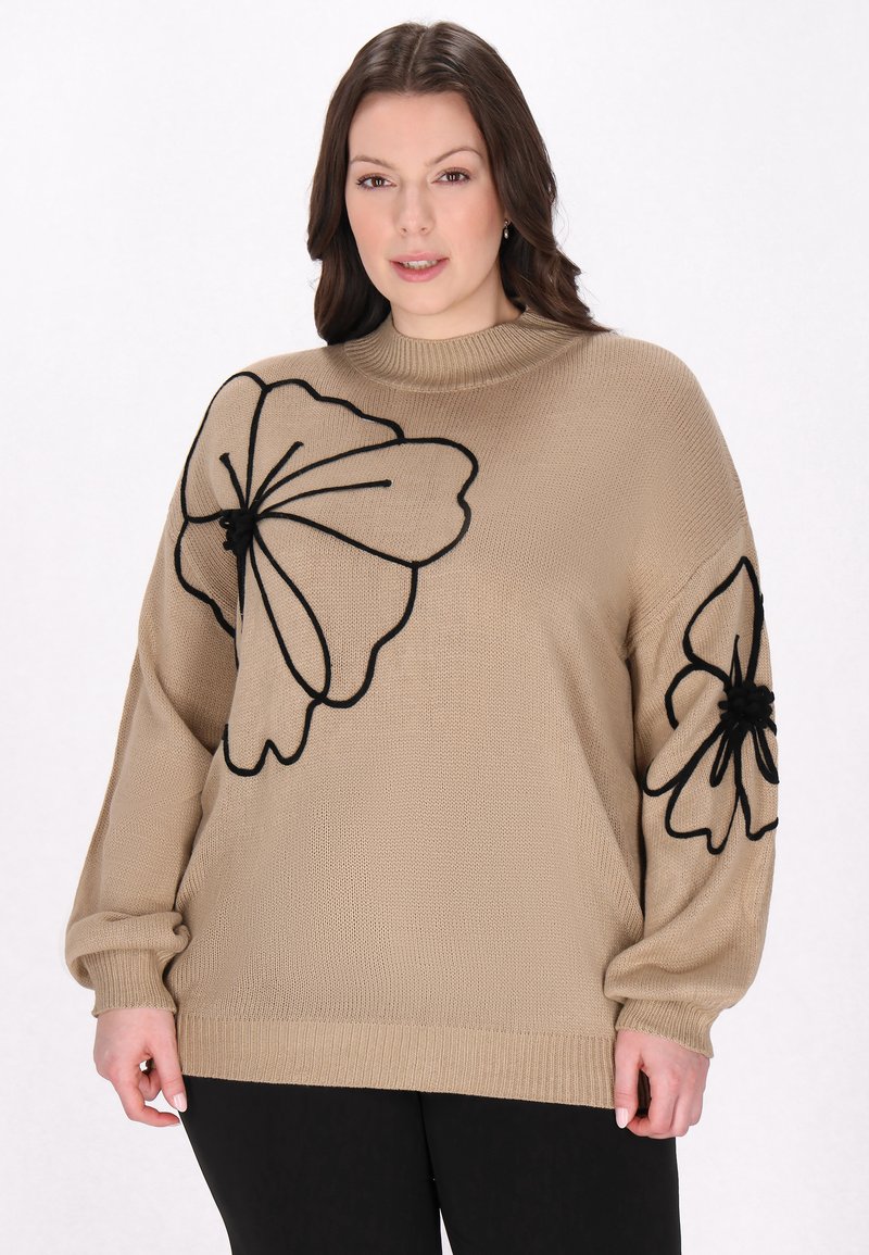 Pull en tricot beige avec broderie florale noire mettant en valeur de grandes fleurs et un col montant ajusté. Manches longues et décontractées.