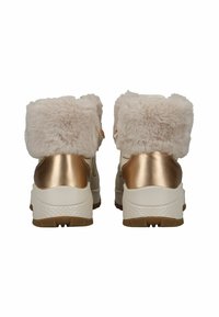 Bottes de cheville blanches et dorées avec une bordure en fausse fourrure beige clair et moelleuse, et une semelle blanche texturée. Présente un accent de talon en métal doré.