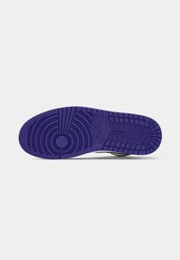 Σόλα αθλητικού παπουτσιού με μοβ καουτσούκ λαβή, κυκλικά και δίχτυα μοτίβα, και κεντρικό ανάγλυφο λογότυπο Nike σε λευκό φόντο.