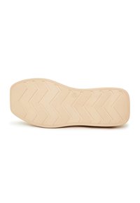 Semelle de chaussure beige avec un motif de bande de roulement en zigzag et des zones de grip texturées, photographiée sur fond blanc.