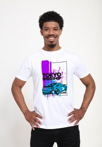 Bílý bavlněný tričko s barevným grafickým designem auta a textem "TOKYO SPEED SHOP" v designu fialové a modré skvrny od barvy.