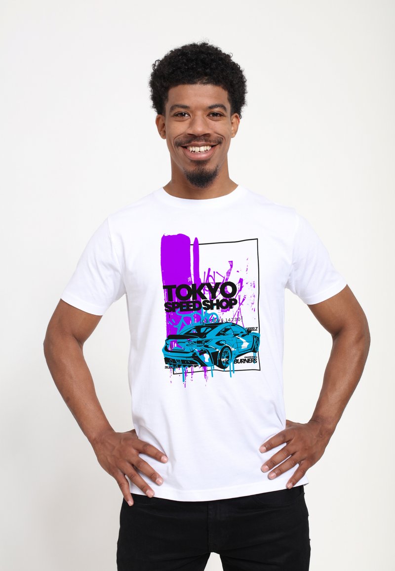 Bílý bavlněný tričko s barevným grafickým designem auta a textem "TOKYO SPEED SHOP" v designu fialové a modré skvrny od barvy.