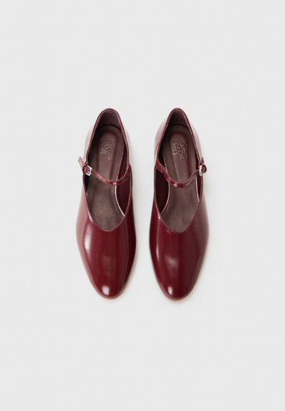Burgundy leather shoes with an almond toe and a single adjustable strap across the ankle. Smooth surface with a glossy finish.