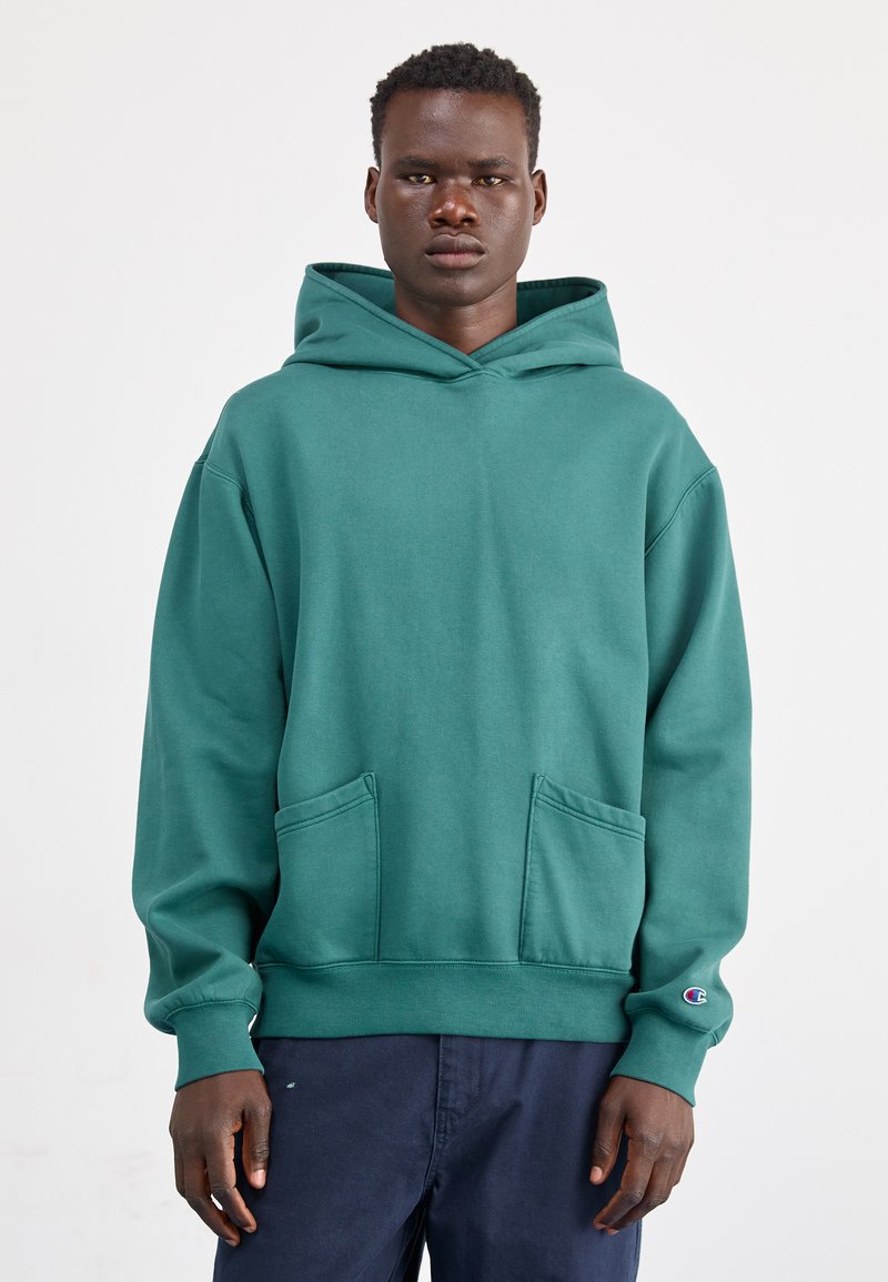 Zielona bluza z kapturem, wykonana z miękkiego materiału. Posiada przednią kieszeń, ściągacze przy mankietach oraz logo na lewym rękawie. Luźny krój.