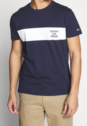 Granatowy bawełniany t-shirt z białym poziomym pasem z logo "TOMMY JEANS". Krótkie rękawy, okrągły dekolt i miękka tekstura.