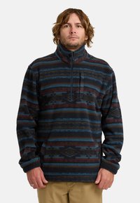 Fleece pullover met een kwart-rits, met blauwe, bordeauxrode en zwarte horizontale strepen en geometrische patronen. Zachte textuur, ontspannen pasvorm.
