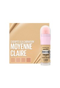 Maybelline Perfecter 4-en-1 Glow Makeup dans une teinte medium clair, avec un design cylindrique, un applicateur rose et un fond beige.