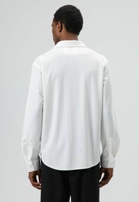 Wit overhemd met lange mouwen, een gladde textuur, klassieke kraag en knoopmanchetten, voorzien van een afgeronde zoom en een losse pasvorm.