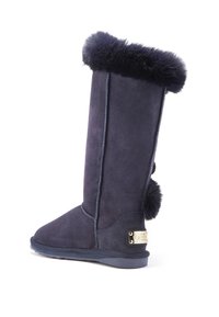 Knee-high tmavo modré semišové čižmy s jemným umelým kožušinovým lemom, okrúhlou špičkou a dekoratívnymi ponpom akcentmi. Obsahujú zlatú značkovú platňu.