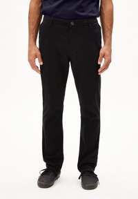 Zwarte chinos van katoen, met een rechte snit, knoopsluiting, zijzakken en een gladde textuur. Draagt bij donkere schoenen.