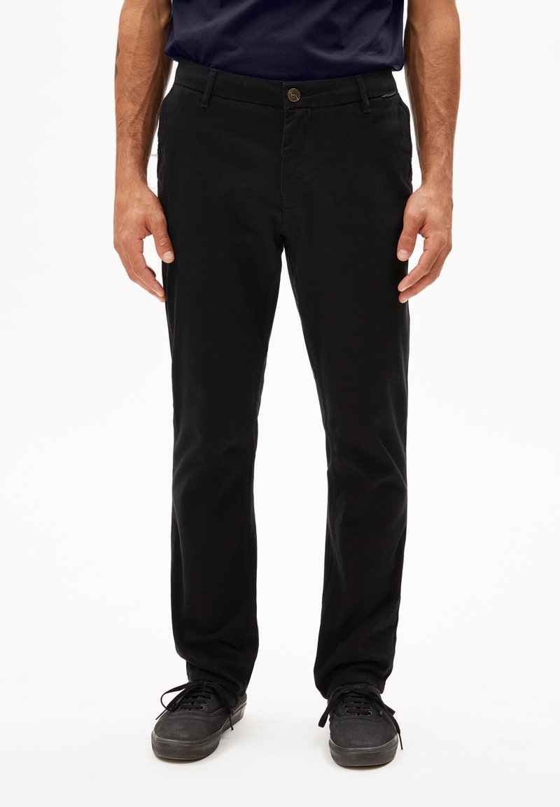 Zwarte chinos van katoen, met een rechte snit, knoopsluiting, zijzakken en een gladde textuur. Draagt bij donkere schoenen.