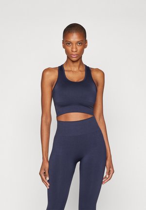 Crop top de sport bleu marine avec un design découpé et des bretelles larges, associé à un legging taille haute de la même couleur et du même matériau.